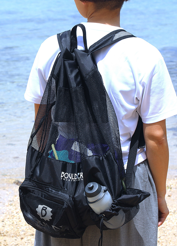BOULDERメッシュバッグを背中にかけて海辺に立つ男性